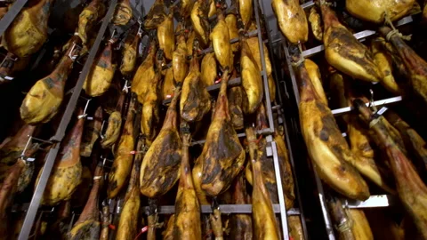 Wide panning shoot of rack full of ham legs hanging in a industry of legs Stock Footage 202522501