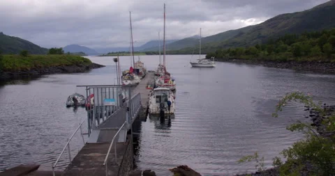 Wide panning shot right to left of boats moored up on a small Marina on the Видео 325833332