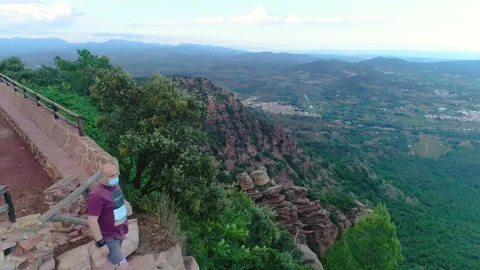 Wide panoramic of valley and man with mask leaning over the edge Stock Footage 138895482