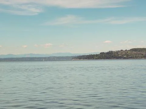 Wide panoramic view of the calm blue sea and distant hills under a soft summe Stock Photos