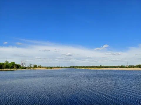 Wide panoramic view of a calm river under a deep blue sky Fotos de archivo