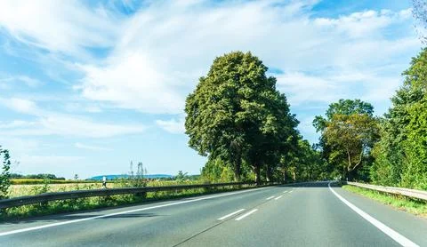 Wide panoramic view of an empty two lane road beside open farmland with a single Stock Photos