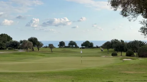 Wide panoramic view of lush green golf course stretches under open sky with Stock Footage 334318073