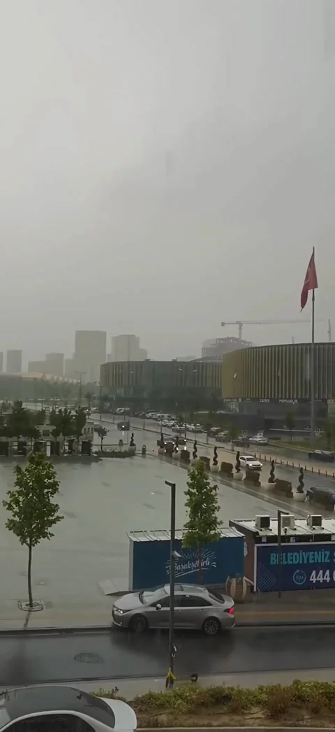 A wide panoramic view of a modern city square during a heavy rainstorm. The Vídeos de archivo 333376135