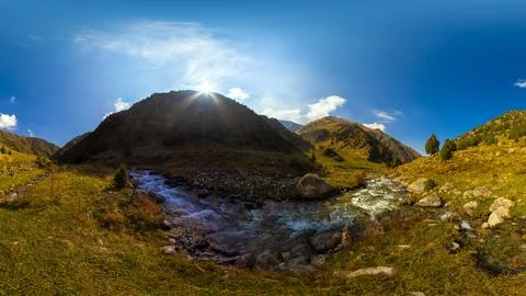 Wide panoramic view of a sunlit mountain valley with two converging streams Фото
