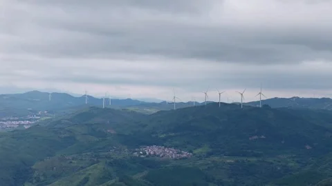 Wide Panoramic View of Wind Farm on Rolling Green Hills Under Overcast Sky Stock Footage 319726786