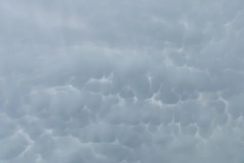 A wide patch of sky strewn with storm clouds in the shape of bubbles. Stock Photos