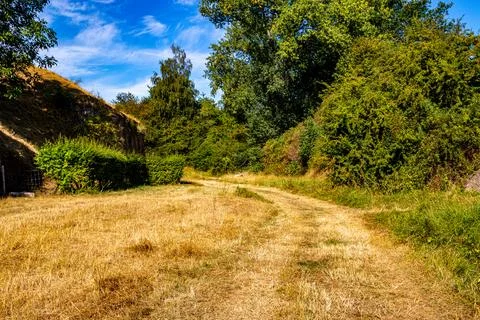 Wide path with dry grass between the walls and hill Stock Photos