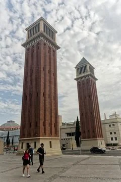 A wide, paved plaza features two red brick towers Stockfoto's