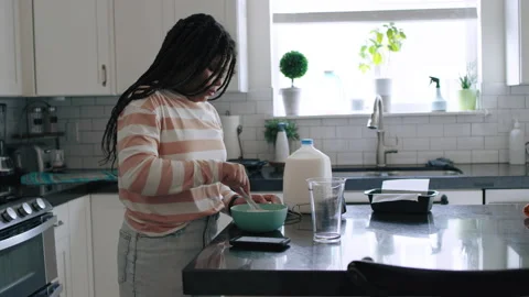 Wide profile side view, female black teenager stirring wet ingredients in bowl 스톡 동영상 194466765