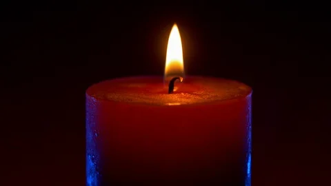 Wide red candle flame on black background with blue rim light Stock Footage 122867834
