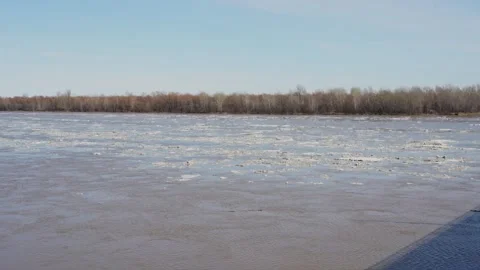 Wide river with floating ice blocks under a clear sky Stock Footage 332434383