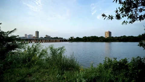 A wide river flows beneath a bridge leading to the city skyline Stock Footage 312679485