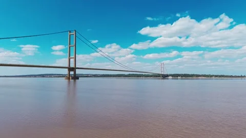 Wide river flows beneath a towering suspension bridge 動画素材 343541023