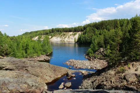 A wide river flows between sandy beaches surrounded by a mixed coniferous for Stock Photos