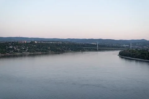 Wide river flows calmly under a soft twilight sky Stock Photos