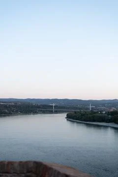 Wide river flows past forested banks under a pale evening sky Stock Photos