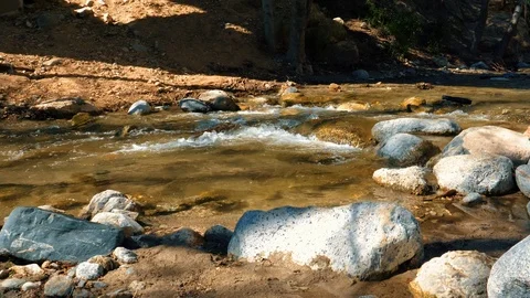 Wide river water flow on the rocks on a sunny day. Mud and river with rocks Stock Footage 105403193