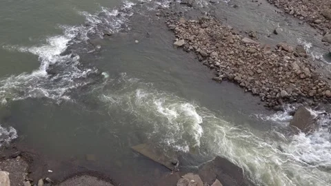 A wide riverbed channel, transitioning from a low-lying rocky island and loose g Stock Footage 342477330