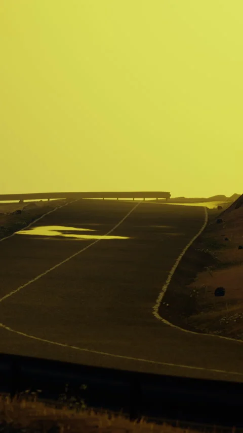Wide road winding through desert landscape under yellow sky Stock Footage 346753864