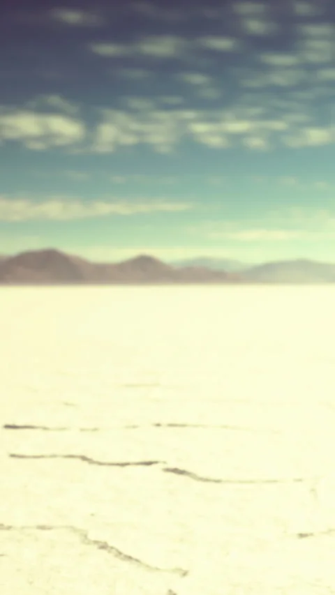 Wide salt flat under blue sky with distant mountains and clouds Stock Footage 337970198