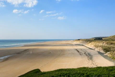 Wide sandy beach and coastal dunes under clear sky Stock Photos