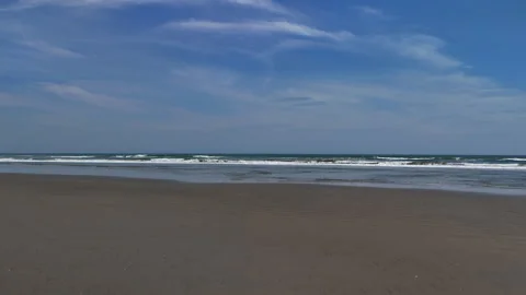 Wide Sandy Beach with Gentle Waves Under a Blue Sky Stock Footage 286963822