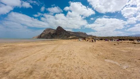 Wide sandy beach with mountain under cloudy blue sky. Socotra, Yemen. Stock Photos