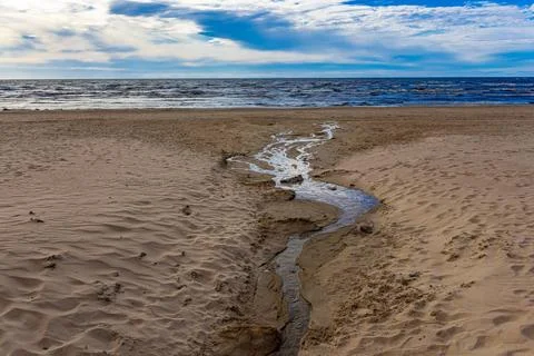 Wide Sandy Beach with Winding Stream Leading to Ocean Stockfoto's