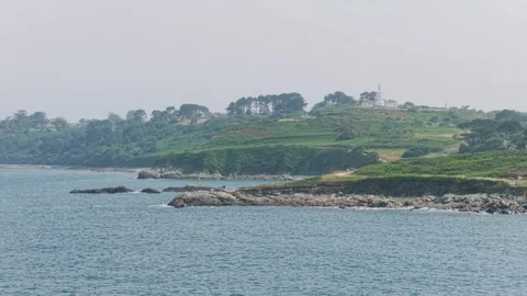 Wide scenic view of the rugged coastline and green cliffs along the Sentier des Stock Footage 346701485