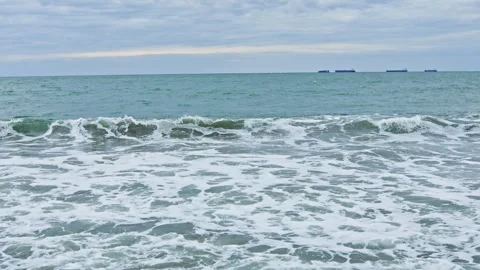 Wide sea setting featuring moving ships and rolling waves along coast. Broad Stock Footage 339490676