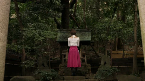 Wide shot on 4k RED camera of somber Japanese woman walking up to a shrine and b Video stock 199458195