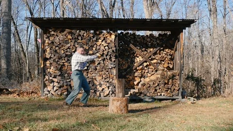 Wide Shot of an Active Senior Man Chopping Firewood in Slow Motion Stock Footage 85643091