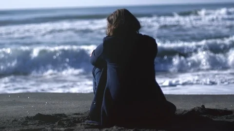Wide shot of back of sad depressed woman in front of waves of ocean in winter Stock Footage 116736056