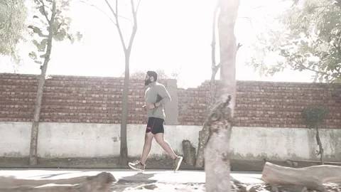 Wide shot of Beard Athlete Man doing jogging  on footpath  in morning Stock Footage 145787772