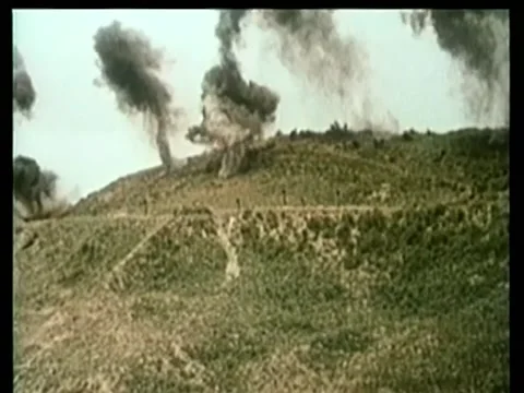 Wide shot bombs exploding on grassy hillside 스톡 동영상 260247474