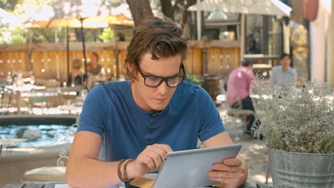 Wide shot of casually dressed student with tablet computer doing homework outdoo Stock Footage 199635109