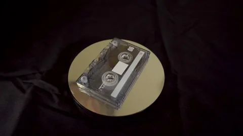 Wide shot of a classic 90s audio cassette on a dark surface. Stock Footage 327624879