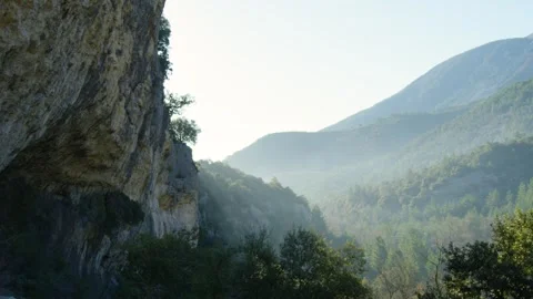 Wide shot of a cliff surrounded by forest of trees at sunrise, in France Stock Footage 240434558