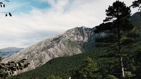 Wide shot of clouds across a mountain ridge above green forest Video stock 324573059
