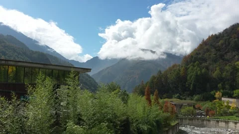 Wide Shot of Clouds Over Mountain Valley with Building and Forest in China Stock Footage 330061590