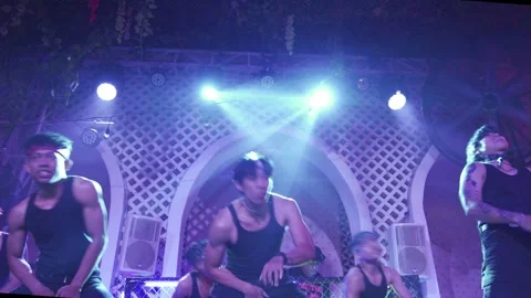 Wide shot of a dance group on a stage under bright spotlights and blue lights 스톡 동영상 337471664