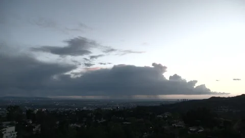 Wide shot dark storm clouds and rain curtains over West Hollywood at sunset Video stock 329170928