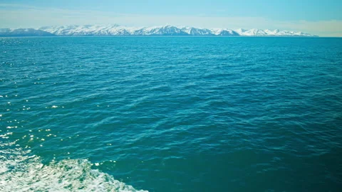 Wide shot of deep blue ocean with distant snow-covered mountains, in Iceland. Stock Footage 293634809