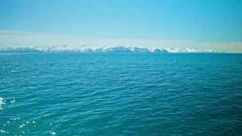 Wide shot of deep blue ocean with distant snow-covered mountains, in Iceland. Stock Footage 293635085