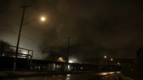 Wide shot desolate street in industrial area rain smoke and street lamp Pan left Stock Footage 89945366