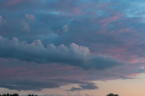 Wide shot of a dramatic sky with layered clouds in shades of pink, purple, an Stock Photos