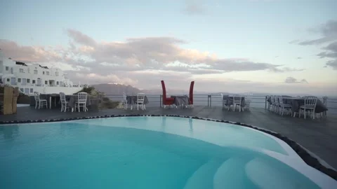 Wide shot of empty poolside restaurant tables on a windy day in Santorini Stock Footage 257673347