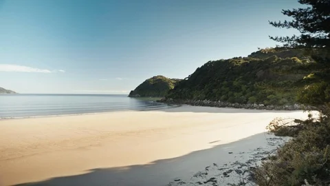 Wide shot of an empty sandy beach clear water green hills Stock Footage 107915913