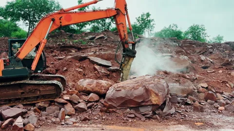 Wide Shot of Excavator Using Hydraulic Breaker to Crush Large Boulder at Stock-Footage 345514055